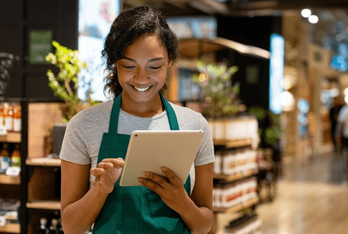 A shop assistant taking a payment on a tablet in a grocery store
